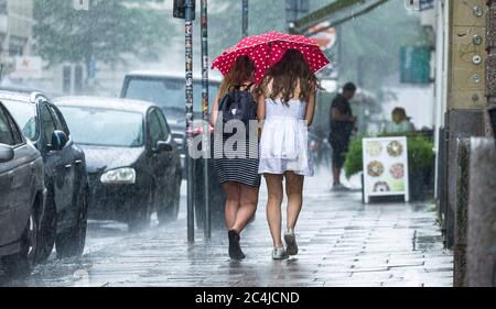 Hambourg, Allemagne. 27 juin 2020. Deux jeunes femmes marchent ensemble sous un parapluie à travers une douche à effet pluie dans le centre-ville. Credit: Markus Scholz/dpa/Alay Live News Banque D'Images