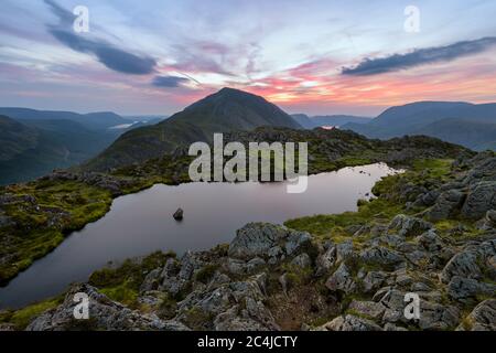 Magnifique coucher de soleil dans les montagnes du Lake District avec Haystacks Tarn. Banque D'Images