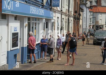 Norfolk, Royaume-Uni. 26 juin 2020. Les gens maintiennent une distance sociale en attendant leurs commandes devant une boutique de Fish & Chips sur la plage. Les gens apprécient le soleil chaud sur la plage de Cromer car le temps en Angleterre a dépassé 30 degrés pour une troisième journée de course. Crédit : SOPA Images Limited/Alamy Live News Banque D'Images