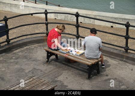 Norfolk, Royaume-Uni. 26 juin 2020. Un couple ayant une pause-collation sur un banc de plage.les gens apprécient le soleil chaud sur la plage de Cromer car le temps en Angleterre a dépassé 30 degrés pour une troisième journée de course. Crédit : SOPA Images Limited/Alamy Live News Banque D'Images