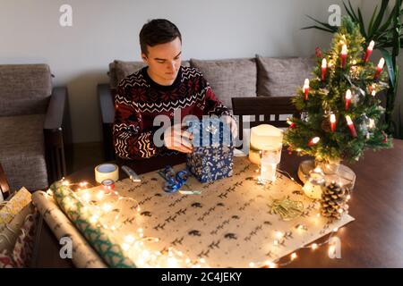 jeune homme emballe des cadeaux de noël pour les amis et la famille Banque D'Images