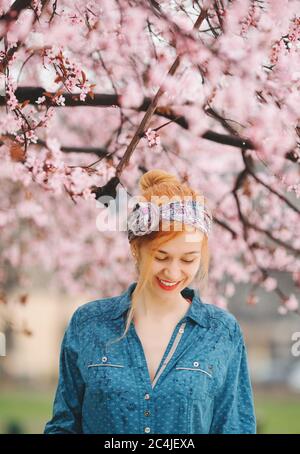 Jeune femme debout sous la pluie sous la fleur du printemps arbre Banque D'Images