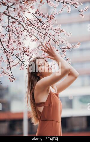Portrait de mode de la jeune femme en combinaison sous la fleur arbre Banque D'Images