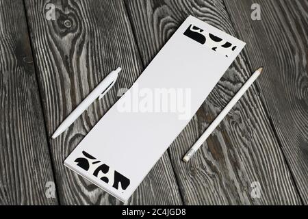 Un carnet ouvert, un crayon blanc et un stylo reposent sur des planches de pin peintes en noir et blanc. Banque D'Images