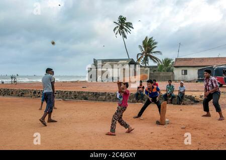 Les garçons musulmans jouent au cricket sur des terres adjacentes à la plage de Negombo au Sri Lanka à l'aube. Banque D'Images