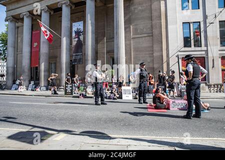 Westminster, le 26 juin 2020. Londres, Royaume-Uni. Les militants des droits des animaux se réunissent en face de la Maison canadienne à Trafalgar Square pour démontrer la mort de Regan Russell, tué à l'extérieur d'un abattoir de l'Ontario lorsqu'il a été frappé par un camion. Deux activistes se sont mis dans la rue attachée l'un à l'autre. La police intervient pour contenir les manifestants. Banque D'Images