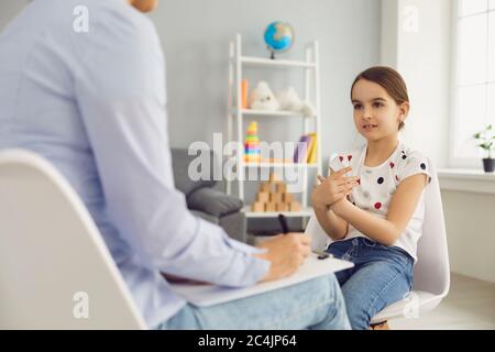 Jolie petite fille parlant à l'enfant psychothérapeute au bureau médical. Traitement des problèmes de santé mentale Banque D'Images