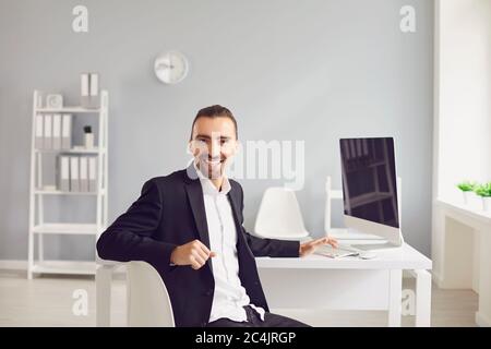 Un homme brunette dans une veste noire assise à la table travaille avec des papiers au bureau. Banque D'Images