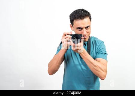 Homme souriant avec un appareil photo entre les mains regardant l'appareil photo. Photo intermédiaire. Fond blanc. Banque D'Images