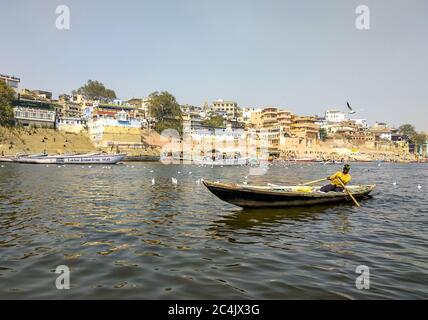 Manmandir Ghat, Gange, Varanasi, Uttar Pradesh, Inde; 30-Jan-2019; un pêcheur rasant un bateau dans le Gange et quelques oiseaux migrateurs sibériens Banque D'Images