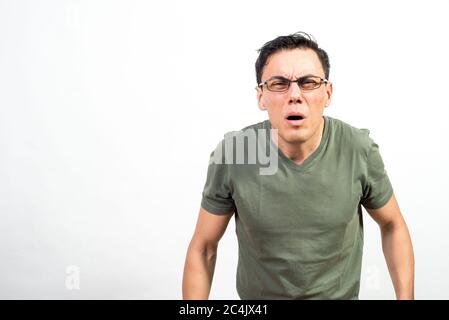 Homme avec des lunettes qui lui mettent les yeux sous tension parce qu'il ne peut pas bien voir. Photo intermédiaire. Fond blanc. Banque D'Images