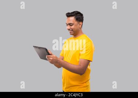 Indian Man utilisant la tablette. Garçon indien avec tablette dans les mains. Livraison à domicile, livraison technique Banque D'Images