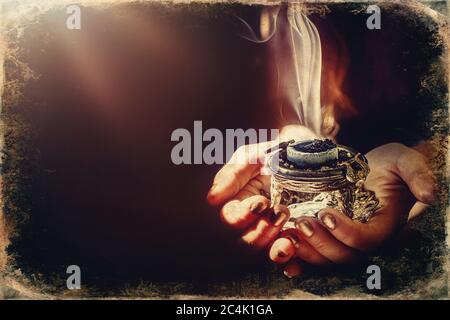 encens dans une main de femme, fumée d'encens sur fond noir. Ancien effet photo. Banque D'Images