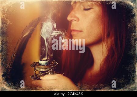 encens dans une main de femme, fumée d'encens sur un fond flou. Ancien effet photo. Banque D'Images