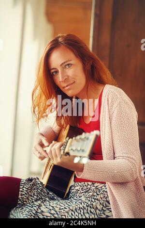femme jouant avec la guitare et un arrière-plan flou. Banque D'Images