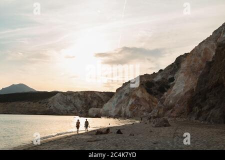 Un couple marchant le long de la plage pendant un coucher de soleil spectaculaire à la plage de Firiplaka à Milos, Grèce Banque D'Images