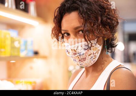 Portrait d'une femme portant un masque facial à l'intérieur d'un établissement commercial. Mise au point sélective. Concept de nouvelle normale. Banque D'Images