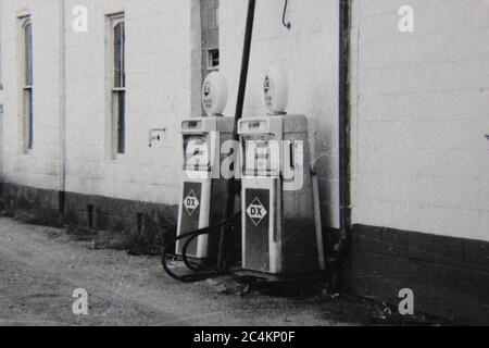 Fin années 70 vintage noir et blanc de style de vie photographie d'un couple pompes à carburant sur le côté de l'allée. Banque D'Images