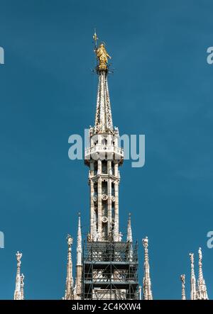 Madonnina au sommet de la cathédrale de Milan à 108.5 m de haut à Milan, en Italie. Statue d'or de Madonna sur la flèche sur fond bleu ciel. Célèbre Milan ca Banque D'Images