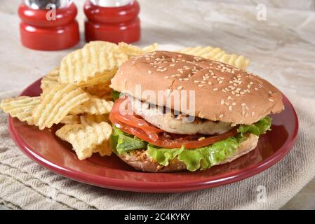 Un hamburger de saumon grillé et sain avec des chips de pommes de terre coupées en petits morceaux Banque D'Images