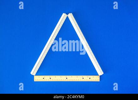 triangle formé de trois règles sur fond bleu vif Banque D'Images