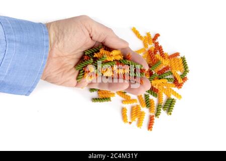 un cuisinier mâle avec une main pleine de pâtes fusilli de couleur végétale isolées sur blanc Banque D'Images