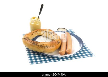 Un grand bretzel de Hambourg et deux saucisses de Vienne sur une assiette bleue et un pot de moutarde parisienne isolée sur blanc Banque D'Images