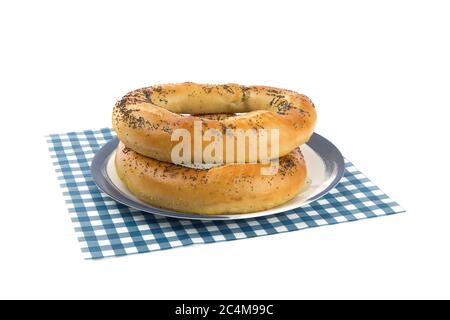 deux énormes bretzels de graines de pavot sur une plaque bleue isolée sur blanc Banque D'Images