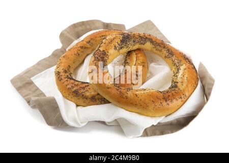 Deux grands bretzels de graines de pavot allemandes sur une serviette brune isolée sur blanc Banque D'Images