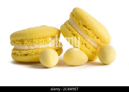 Macro extrême gros plan de biscuits macareux jaunes et mini œufs de Pâques jaunes sur fond blanc Banque D'Images