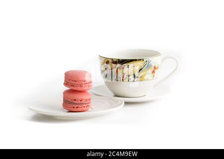 biscuits macareux roses avec une tasse de thé colorée sur fond blanc Banque D'Images