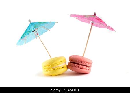 biscuits meringues colorés avec parasols sur fond blanc Banque D'Images