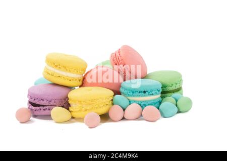 Un gros plan d'une assiette pleine de biscuits meringue colorés et mini oeufs de Pâques pastel sur un fond blanc Banque D'Images