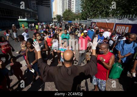 26 juin 2020, Rio de Janeiro, Rio de Janeiro, Brésil : Un Friar dit une prière avant le début de la distribution de nourriture. Devant une ligne de personnes dans une situation vulnérable qui est formée pour recevoir de la nourriture d'une action franciscaine qui donne des repas aux sans-abri et aux chômeurs à Largo da Carioca, Au centre-ville de Rio de Janeiro, dans le contexte des répercussions croissantes du nouveau coronavirus pandémique. L'action, menée par des volontaires et des frères du Service de solidarité franciscain (Sefras), en partenariat avec le couvent de Santo antínio et la paroisse de São bonifacio, en Allemagne, a alrea Banque D'Images