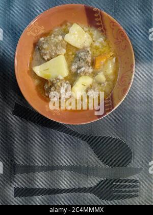 Dose verticale de soupe de boulettes de viande avec pomme de terre et courge dans un bol sur un napperon Banque D'Images