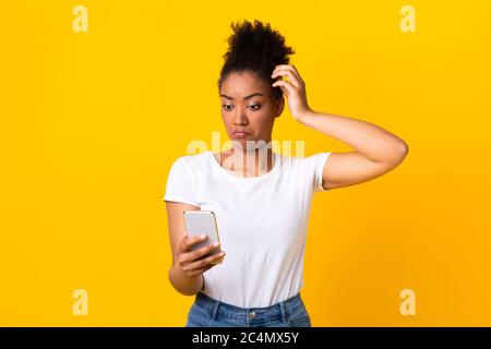 Confusion chez la jeune femme africaine utilisant un téléphone portable Banque D'Images