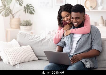 Heureux couple afro-américain naviguant sur Internet sur un ordinateur portable à la maison Banque D'Images