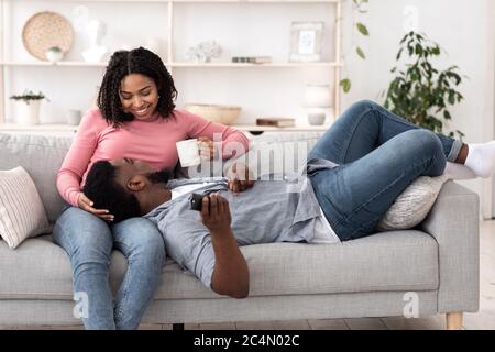 Séjour confortable à la maison. Couple noir romantique se relaxant ensemble sur un canapé Banque D'Images