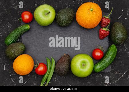 Fruits et légumes assortis sur fond noir texturé. Vue de dessus, espace de copie. Alimentation saine et biologique et style de vie végétalien. Banque D'Images