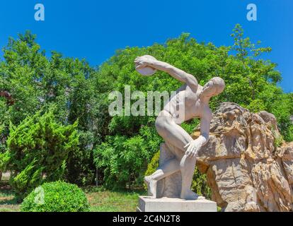 Ciel bleu extérieur, arbre vert et sculpture de lanceur de discus, sculpteur grec Myron fabriqué autour de 450 av. J.-C. Banque D'Images