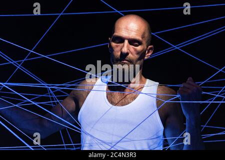 Photo d'un homme adulte emmêlé dans une corde blanche à la lumière du néon Banque D'Images