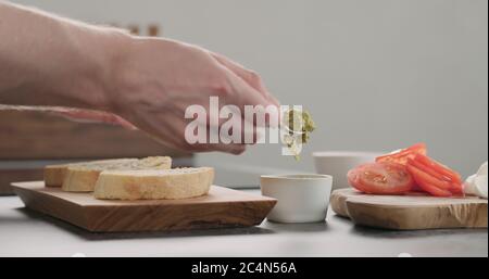 homme répandant du pesto sur une tranche de pain de ciabatta sur un plateau d'olive Banque D'Images