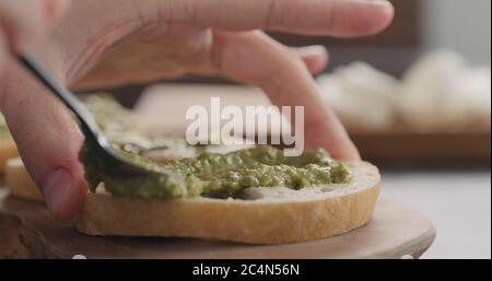 homme répandant du pesto sur une tranche de pain de ciabatta sur un plateau d'olive Banque D'Images