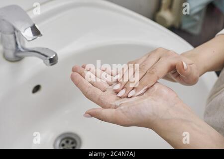 Gros plan d'une femme se lavant les mains avec du savon au-dessus de l'évier Banque D'Images