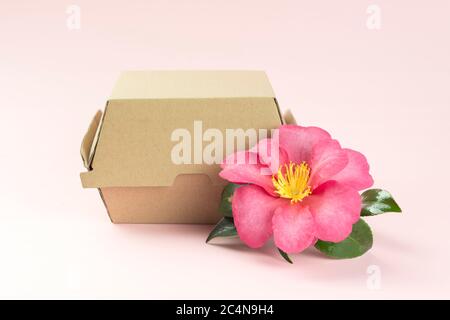 Boîte de hamburger avec fleur sur fond rose clair. Banque D'Images