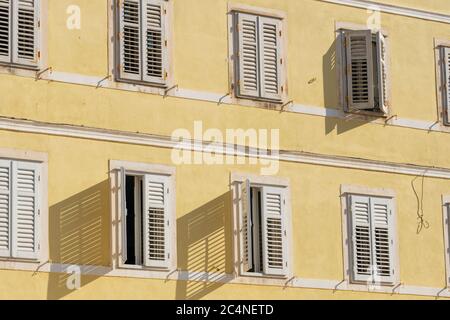 Bâtiment traditionnel de style méditerranéen avec volets blancs sur le mur jaune Banque D'Images