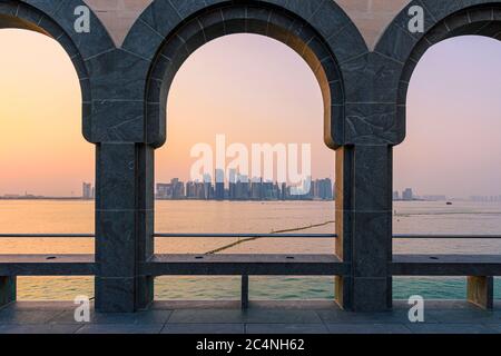 Vue sur la ville de Doha au coucher du soleil à travers les arches de la cour du Musée d'art islamique de Doha, Qatar Banque D'Images