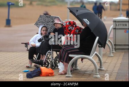 Une famille se fait abriter de la plage de Skegness, car la pluie, le vent et les avertissements météorologiques ont mis fin à la vague de chaleur de juin. Banque D'Images