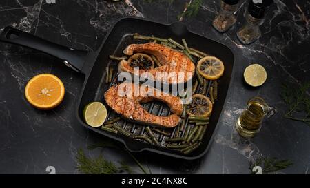 Steaks de saumon grillés aux épices et au jus de citron sur fond sombre. Banque D'Images