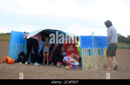 Une famille se protège du temps sur la plage de Skegness, car la pluie, le vent et les avertissements météorologiques ont mis fin à la vague de chaleur de juin. Banque D'Images